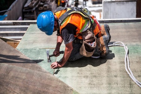 Worker hammering on a roof deck